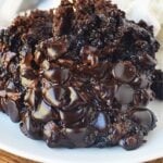 Close up of crockpot lava cake with gooey melted chocolate chips served with vanilla ice cream and cherry.