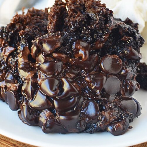 Close up of crockpot lava cake with gooey melted chocolate chips served with vanilla ice cream and cherry.