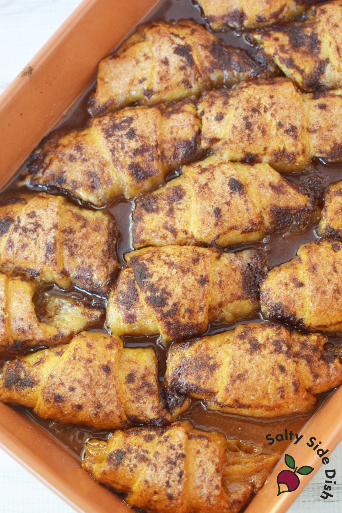 Golden brown Mountain Dew apple dumplings baked in a pan with cinnamon topping