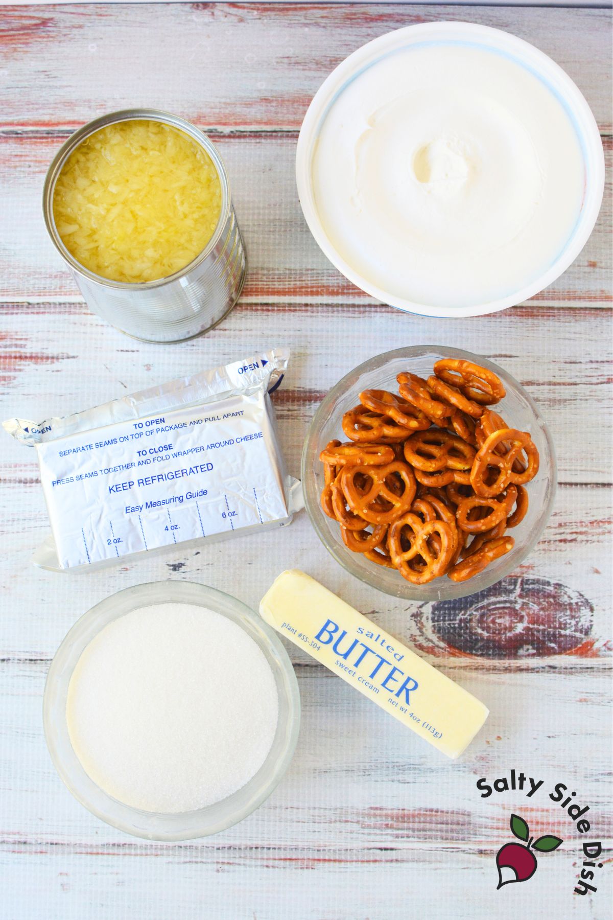 Ingredients for pineapple fluff salad including crushed pineapple, cream cheese, butter, sugar, pretzels, and whipped topping
