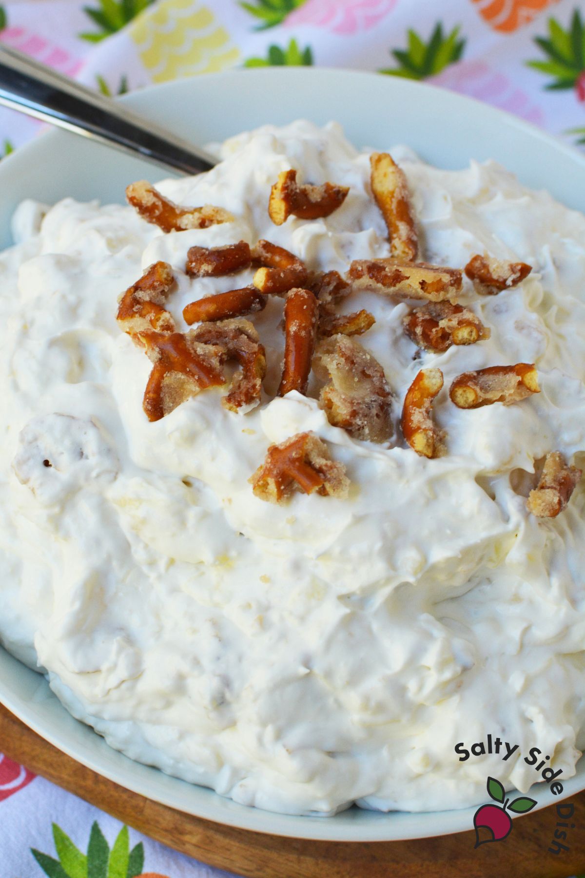 Creamy pineapple pretzel fluff salad in a white bowl, perfect for holidays and potluck side dishes