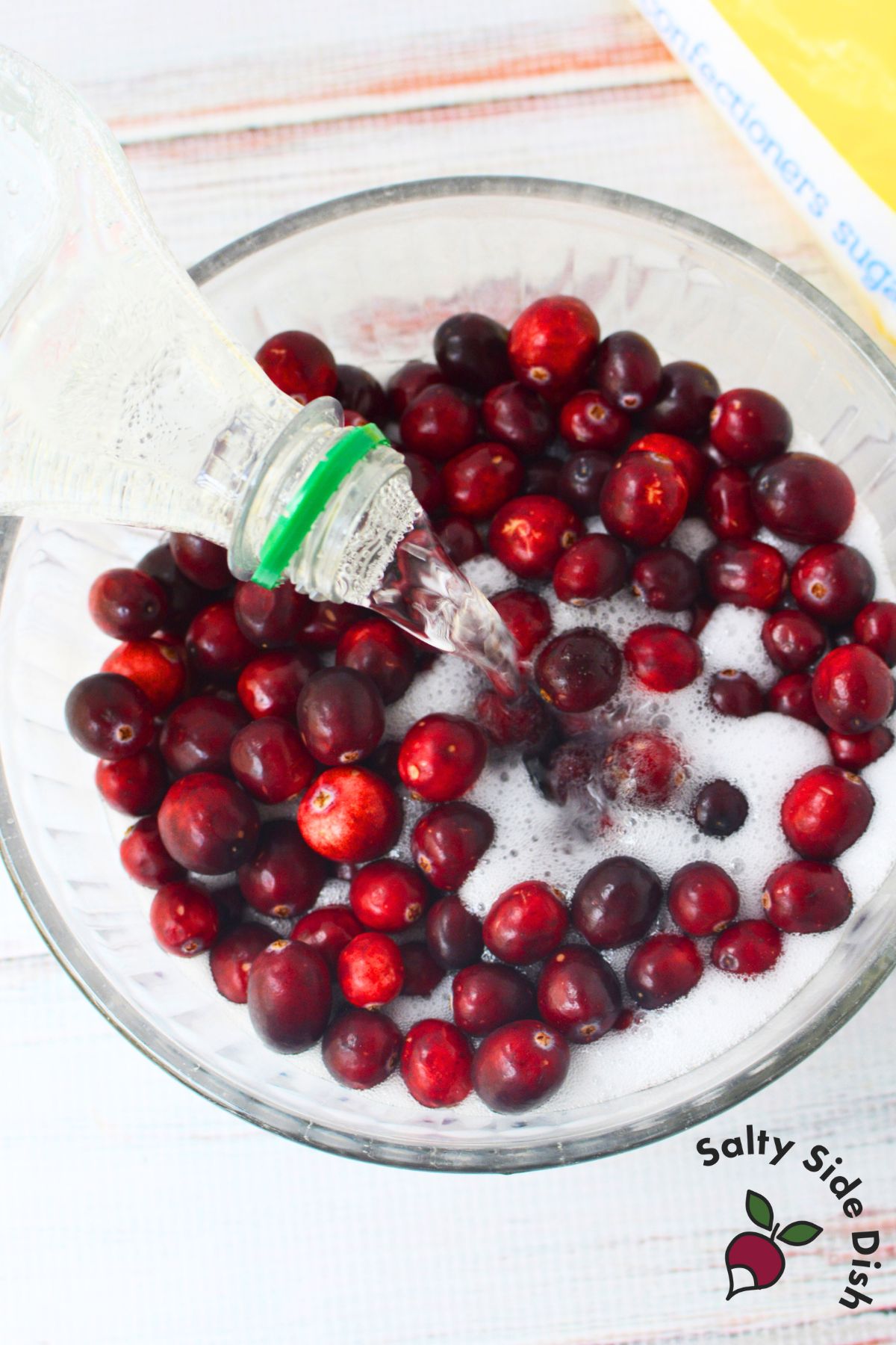 Lemon lime soda being poured over fresh cranberries to soak before making sugared cranberries.