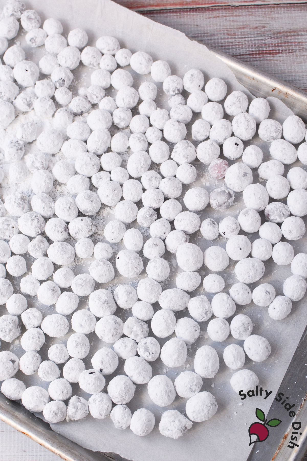 Tray of sugared cranberries coated in powdered sugar, cooling before serving as garnish or snack.