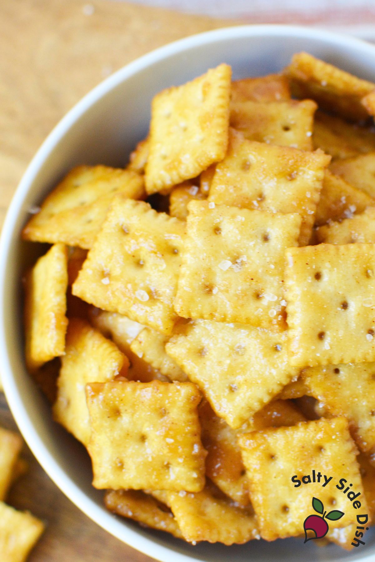 bowl of golden mini saltine crackers with coarse salt on top for caramelized cracker bites