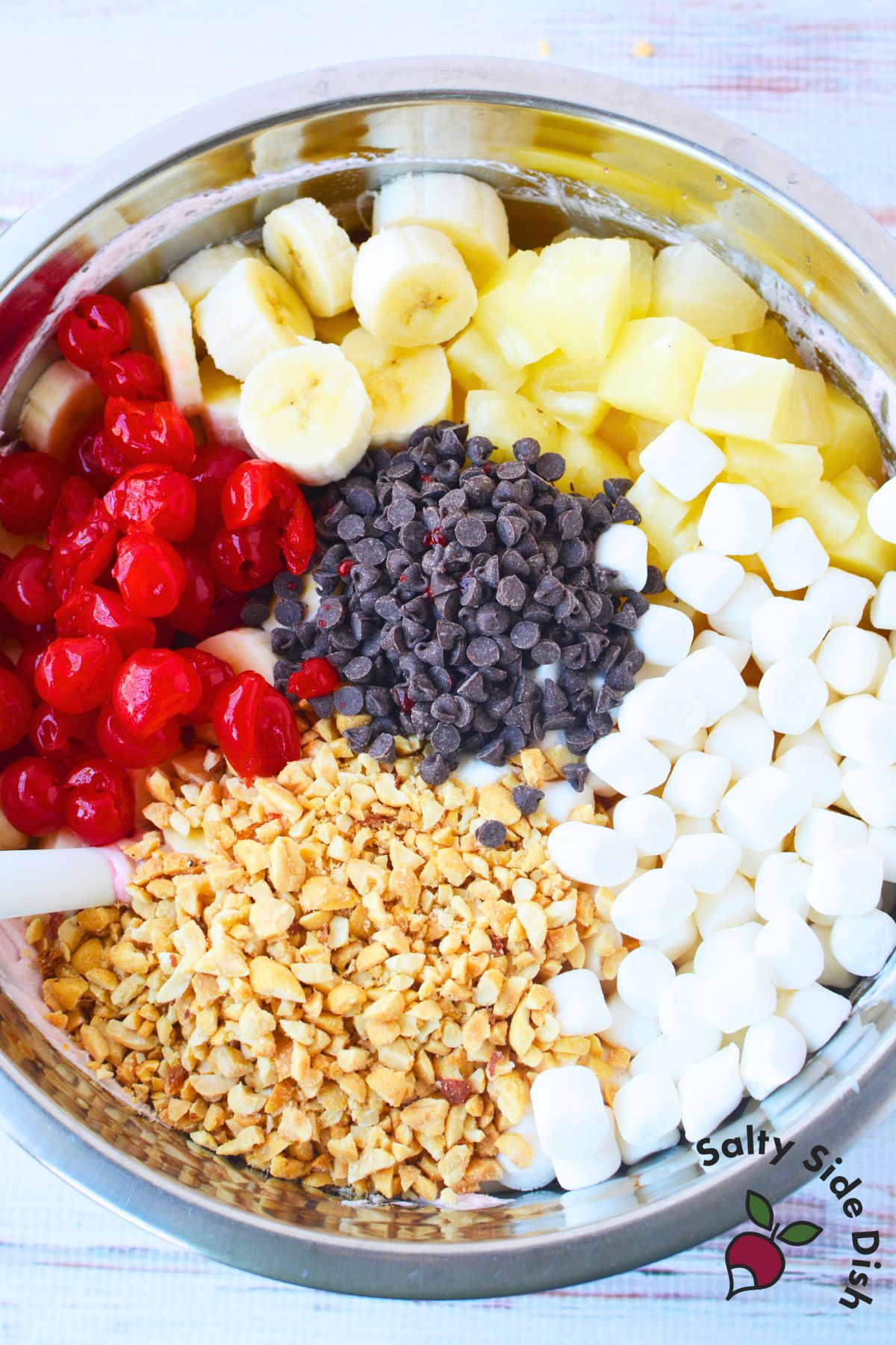 fresh bananas pineapple cherries mini marshmallows peanuts and chocolate chips in a bowl for banana split fluff salad