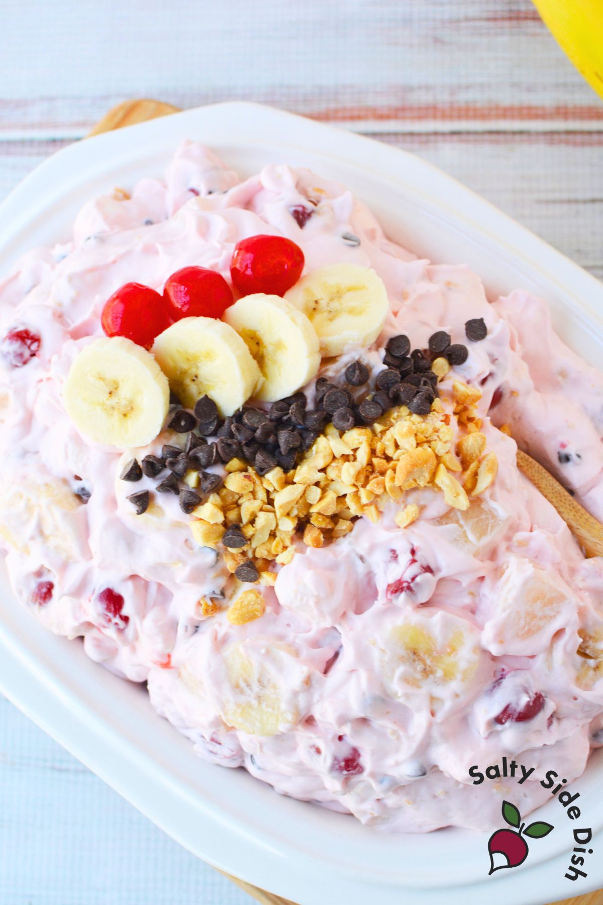 banana split fluff salad topped with maraschino cherries sliced bananas chocolate chips and peanuts