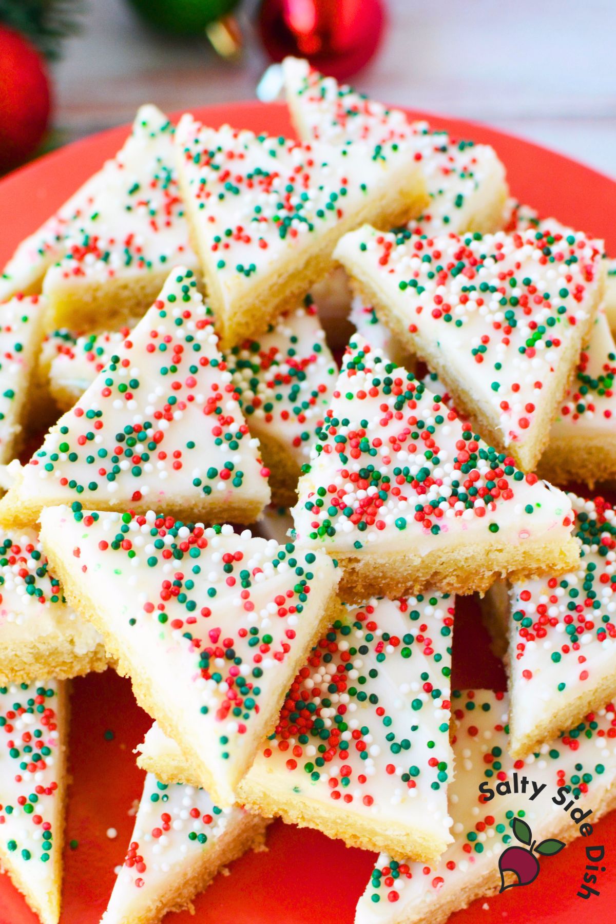 Close up of frosted sugar cookie bars decorated with red, green, and white nonpareil sprinkles