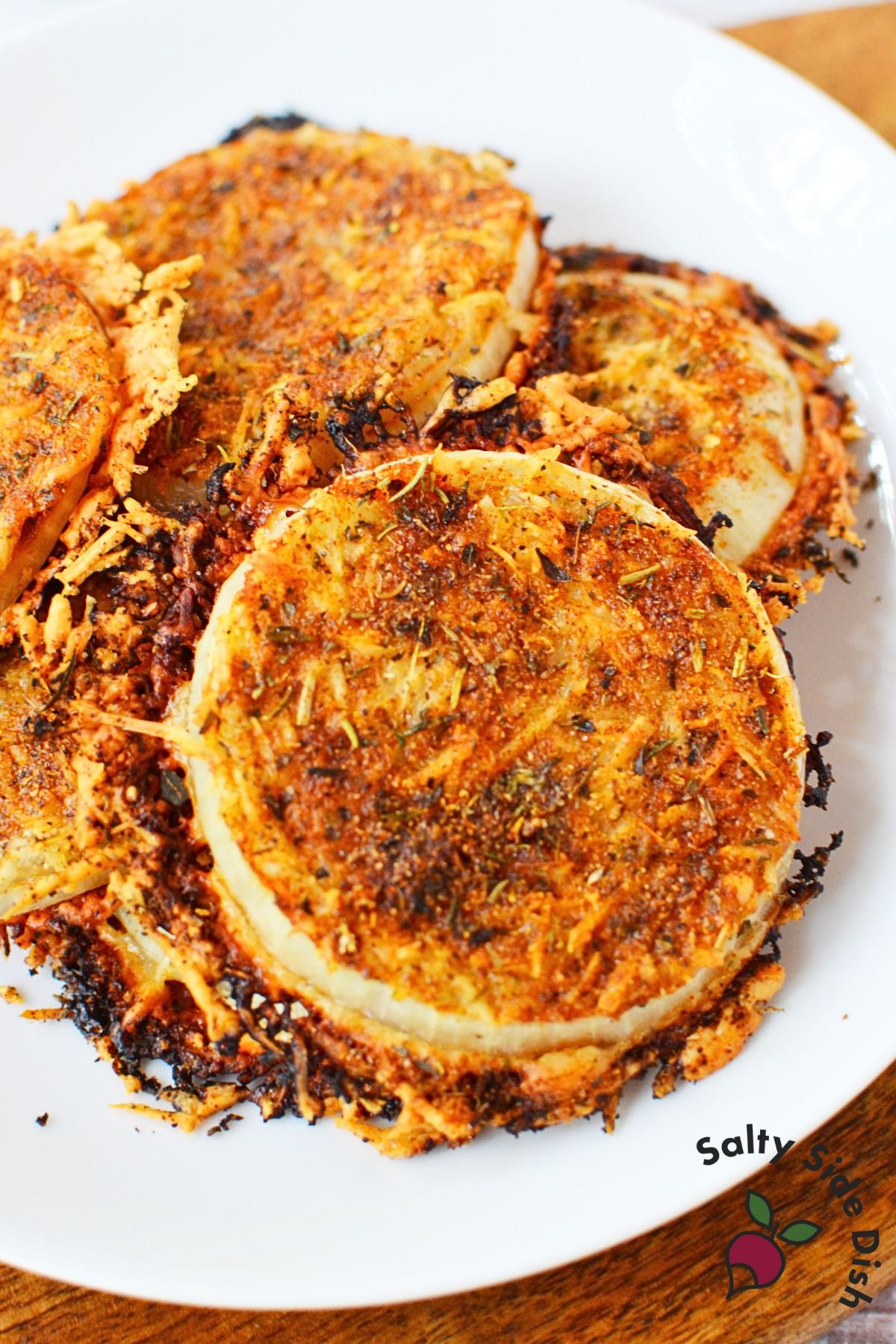 Crispy baked onion rings from viral TikTok recipe on white plate with melted Parmesan edges