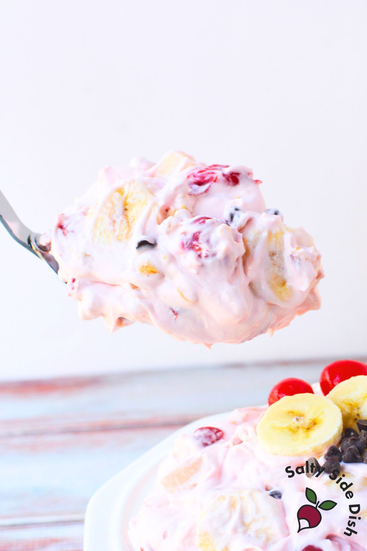 creamy banana split fluff salad with cherries bananas chocolate chips and pineapple in a serving dish