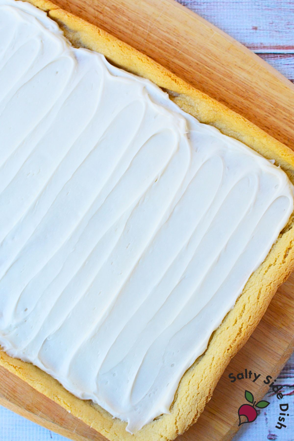 Soft sugar cookie bars frosted with white icing before adding holiday sprinkles