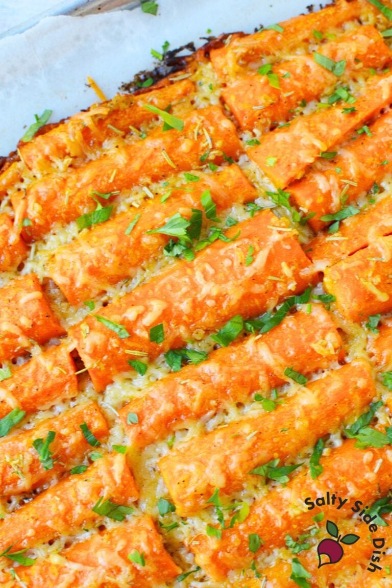 Oven baked garlic parmesan carrots on parchment with melted cheese and parsley — simple and delicious baked carrot recipe.