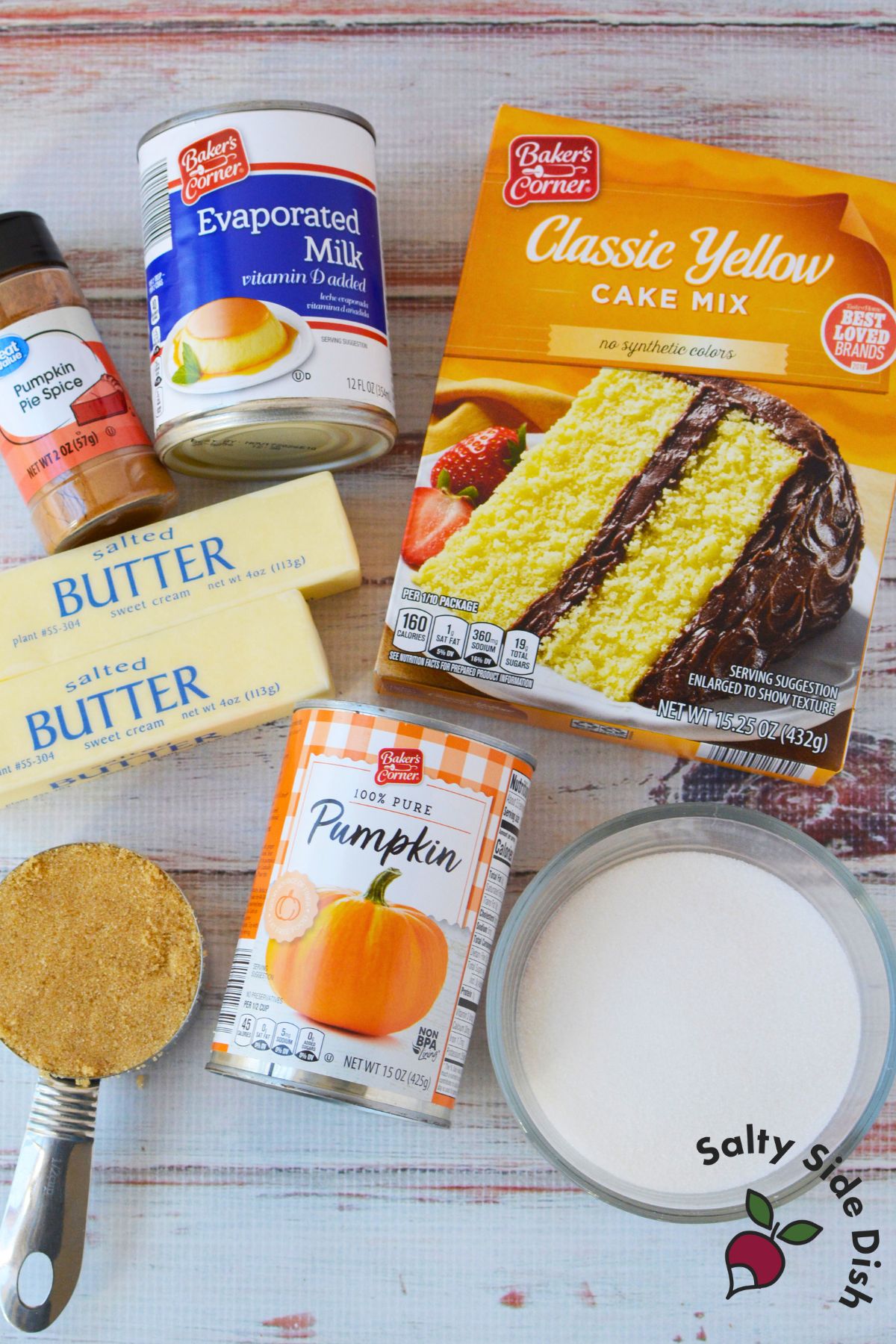 Ingredients for pumpkin pie cake including canned pumpkin, yellow cake mix, butter, evaporated milk, and pumpkin pie spice