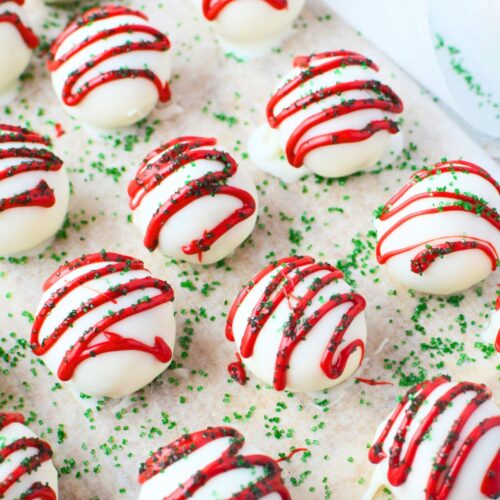 dipped christmas tree cake bites drying on parchment with festive red and green decorations