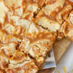 lice of pumpkin pie cake with layers of pumpkin filling and buttery crumble on white plate