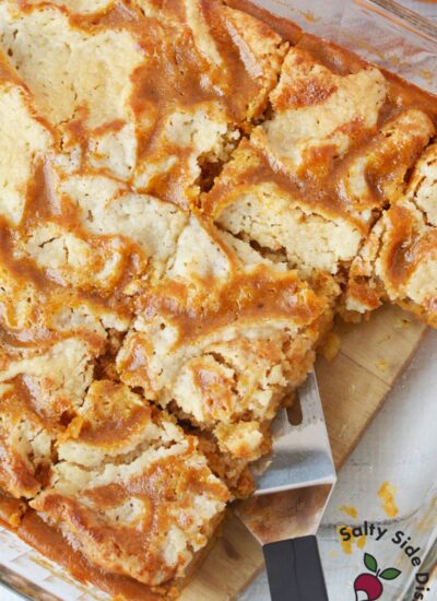 lice of pumpkin pie cake with layers of pumpkin filling and buttery crumble on white plate