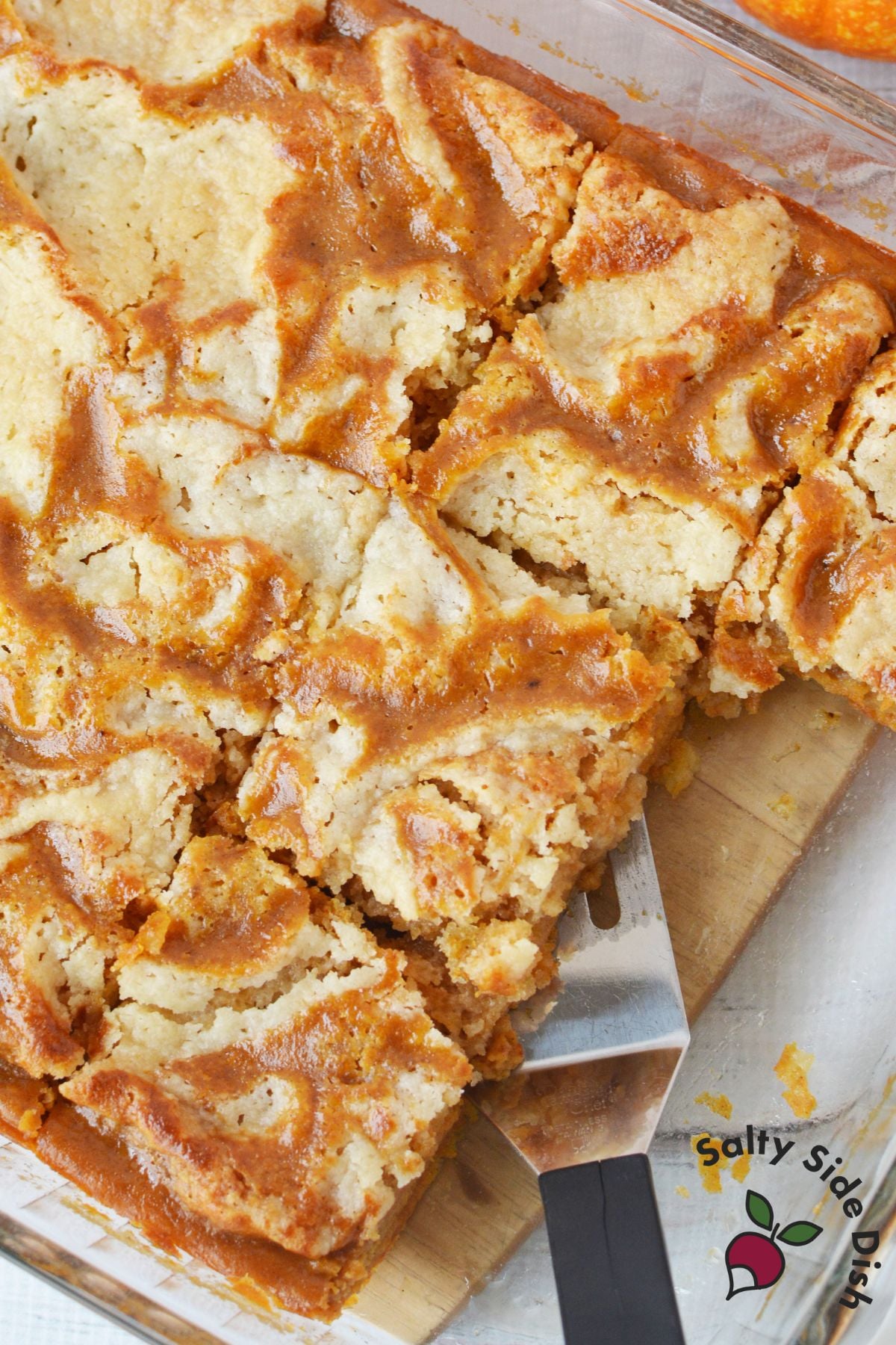 lice of pumpkin pie cake with layers of pumpkin filling and buttery crumble on white plate