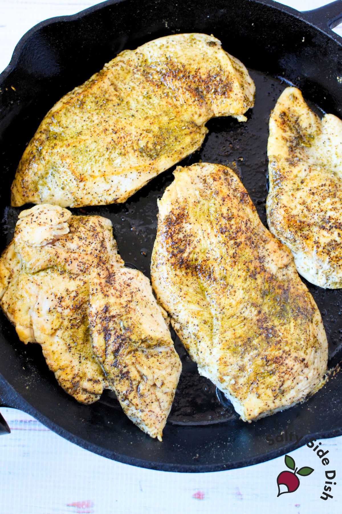 Seasoned chicken breasts searing in a cast iron skillet for a flavorful golden crust.