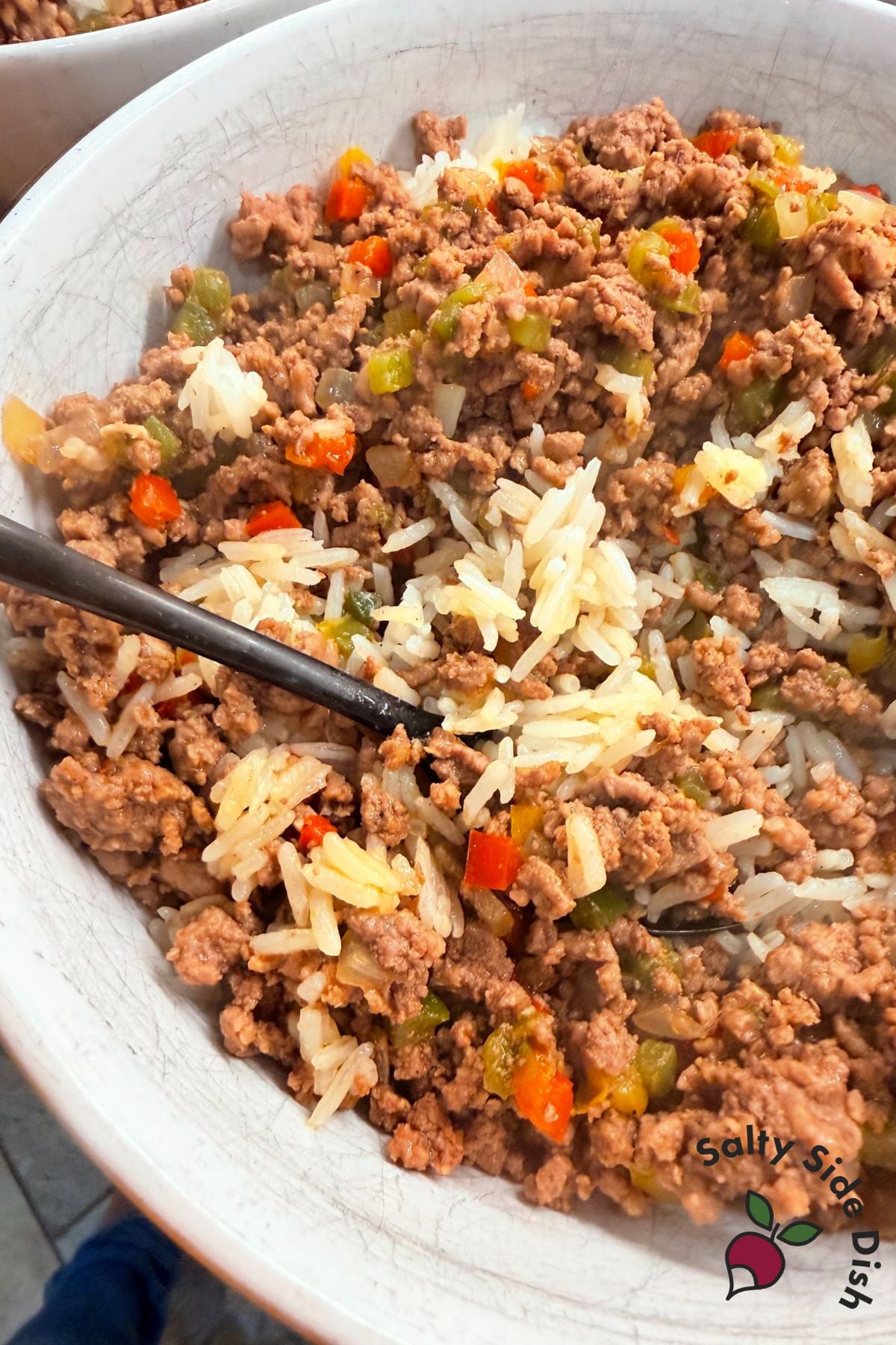 Ground sirloin and diced peppers spooned over jasmine rice in a white bowl with a dark countertop background