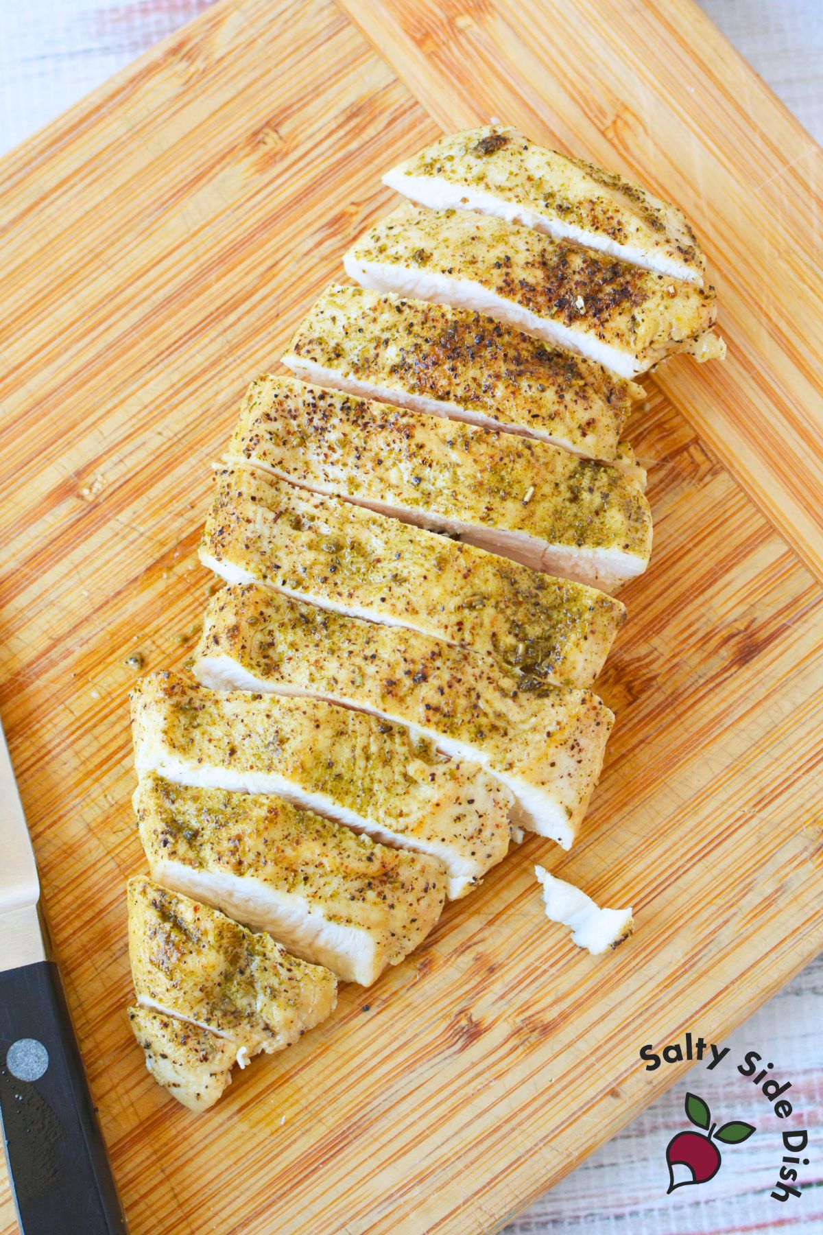 Juicy sliced chicken breast on a wooden cutting board after cooking in a cast iron skillet.