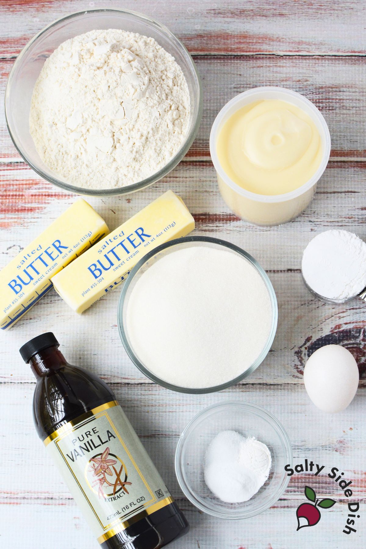 Ingredients laid out for sugar cookie bars recipe including flour, butter, sugar, vanilla, and egg