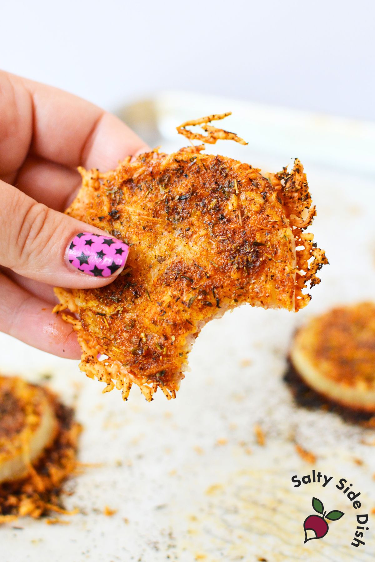 How to make TikTok onion rings with sliced onions layered between shredded Parmesan cheese on parchment paper