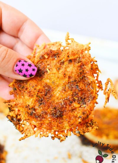 Hand holding a crispy baked TikTok onion ring with melted Parmesan cheese and golden brown edges