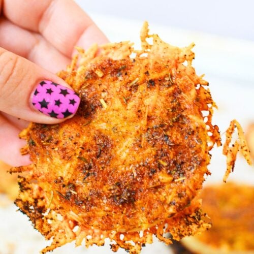 Hand holding a crispy baked TikTok onion ring with melted Parmesan cheese and golden brown edges