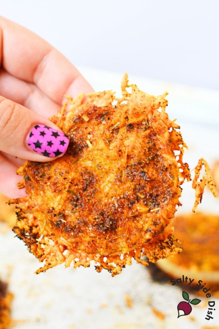 Hand holding a crispy baked TikTok onion ring with melted Parmesan cheese and golden brown edges