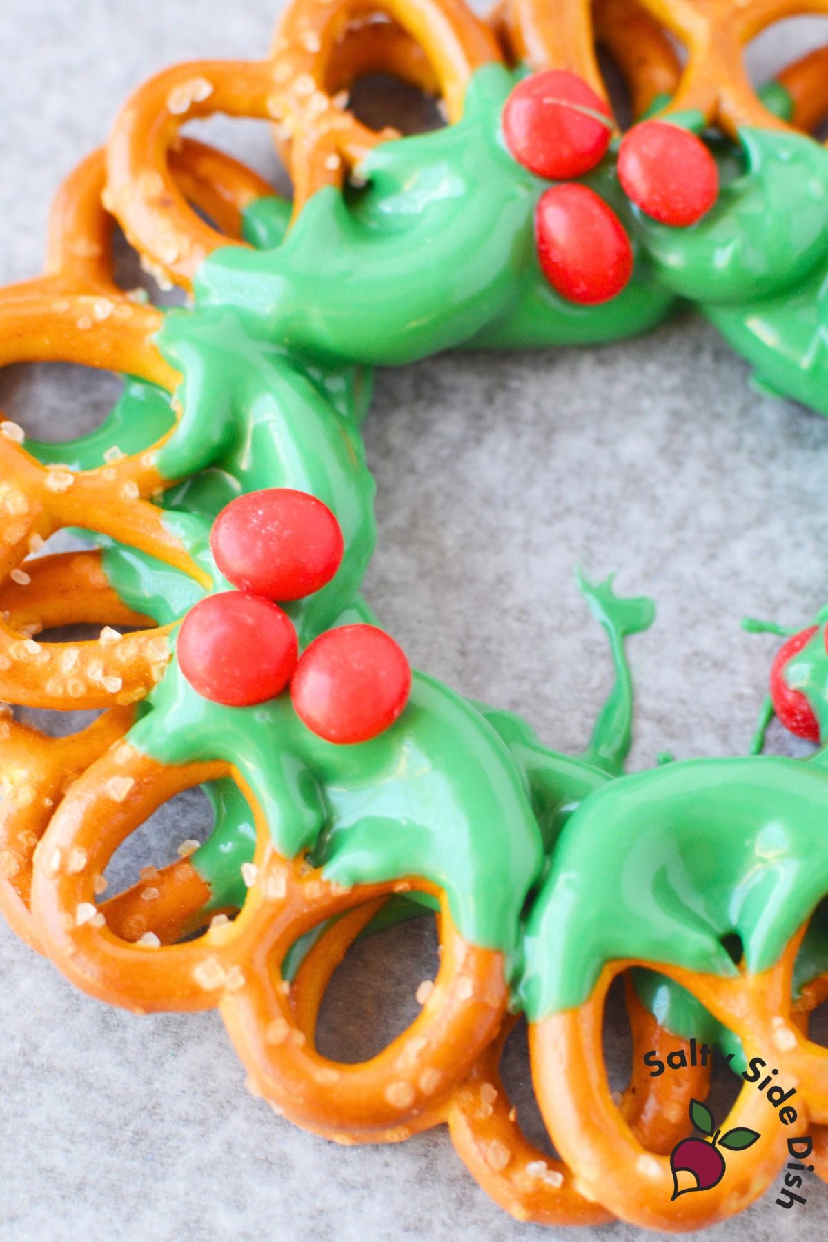 Close up of red cinnamon candy berries on green candy melt coated pretzel wreath