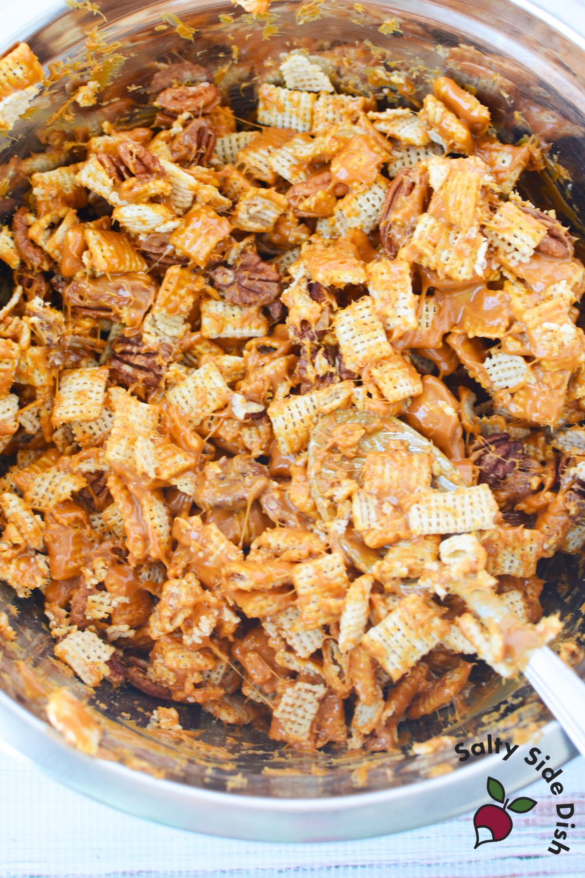 Cereal and pecans coated in melted caramel while mixing caramel pecan clusters