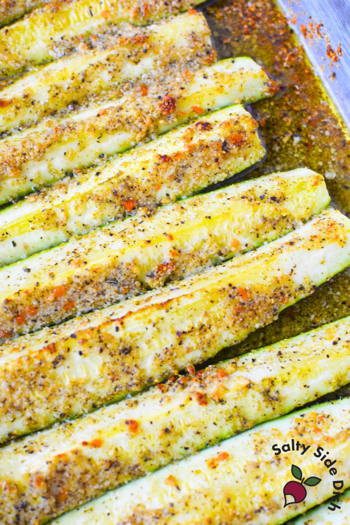 Fork holding a piece of tender parmesan butter roasted zucchini with lightly crisp edges