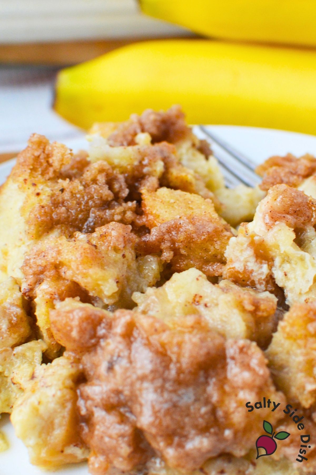 Close up of banana French toast bake with a cinnamon brown sugar crumb topping and soft custard texture