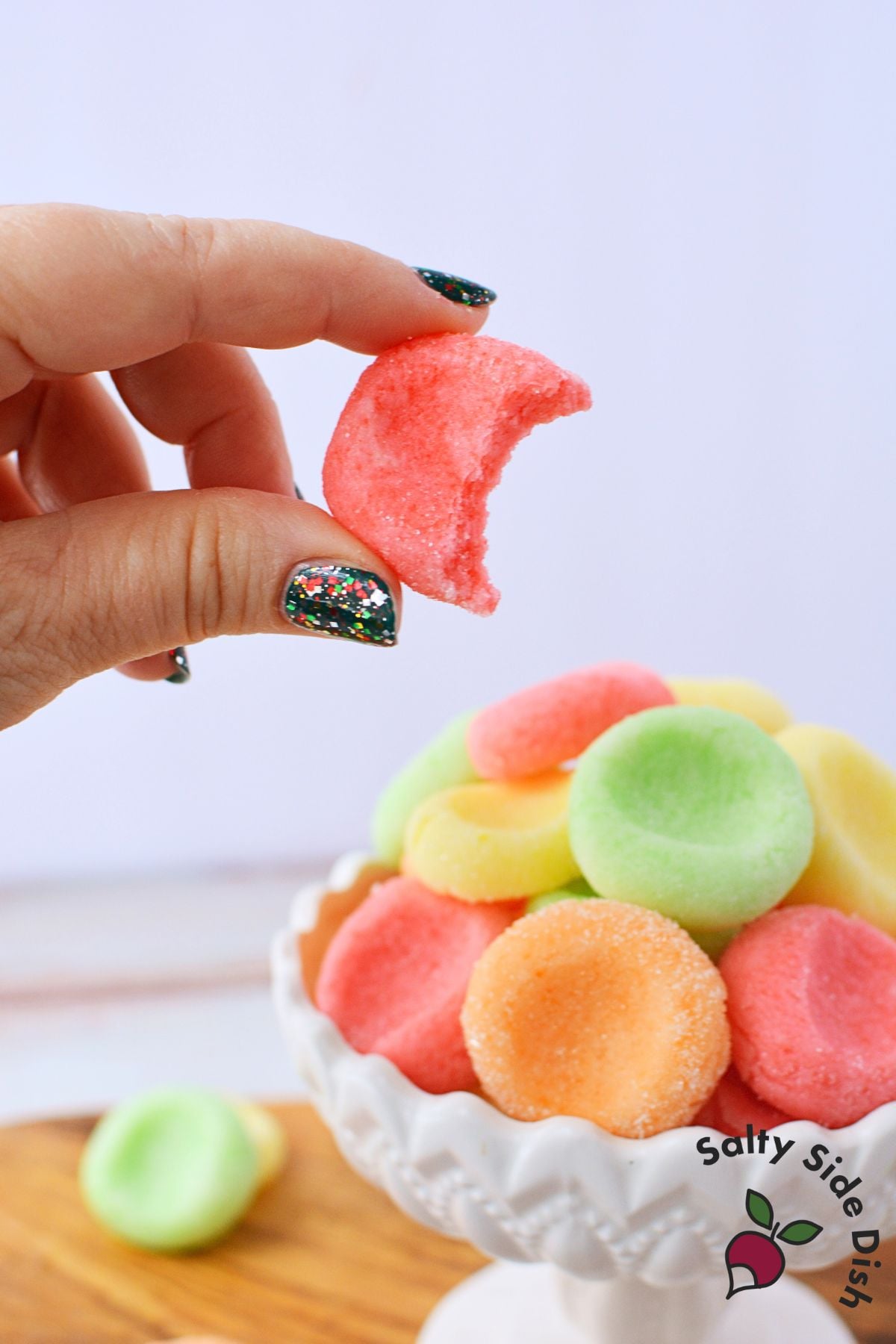 Hand holding a bitten jello candy melt showing soft cream cheese texture