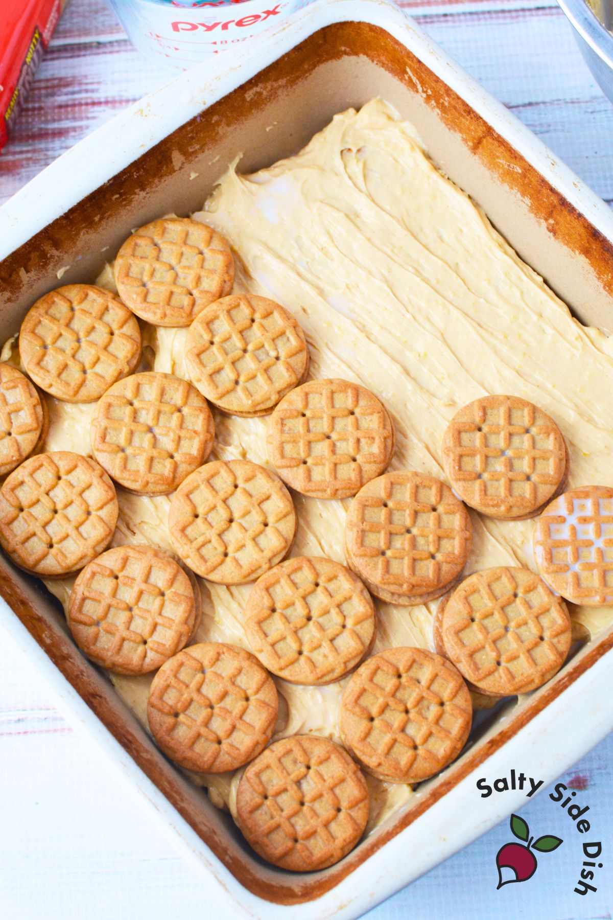 Peanut butter sandwich cookies layered over pudding mixture in a baking dish for icebox cake