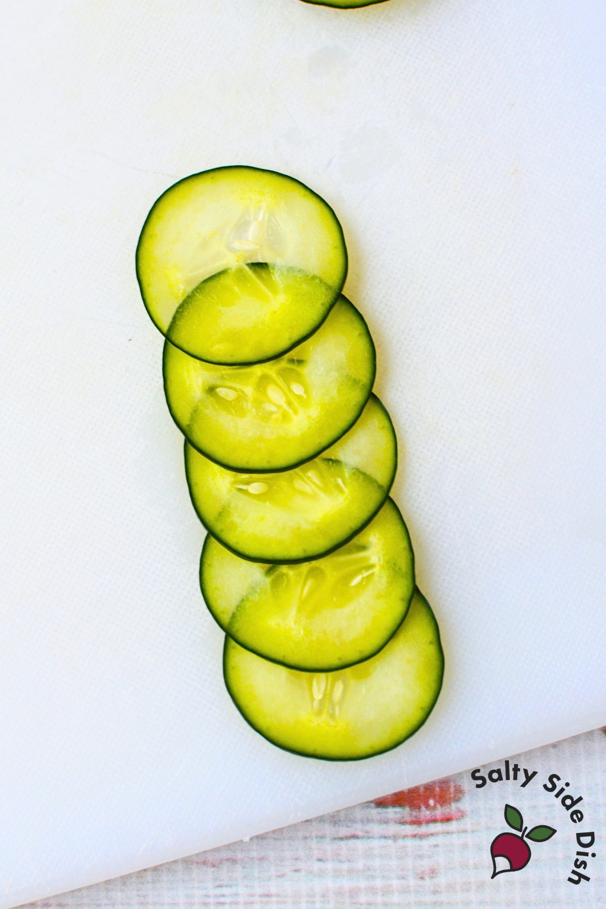 Thin cucumber slices overlapped on a cutting board for rolling into roses