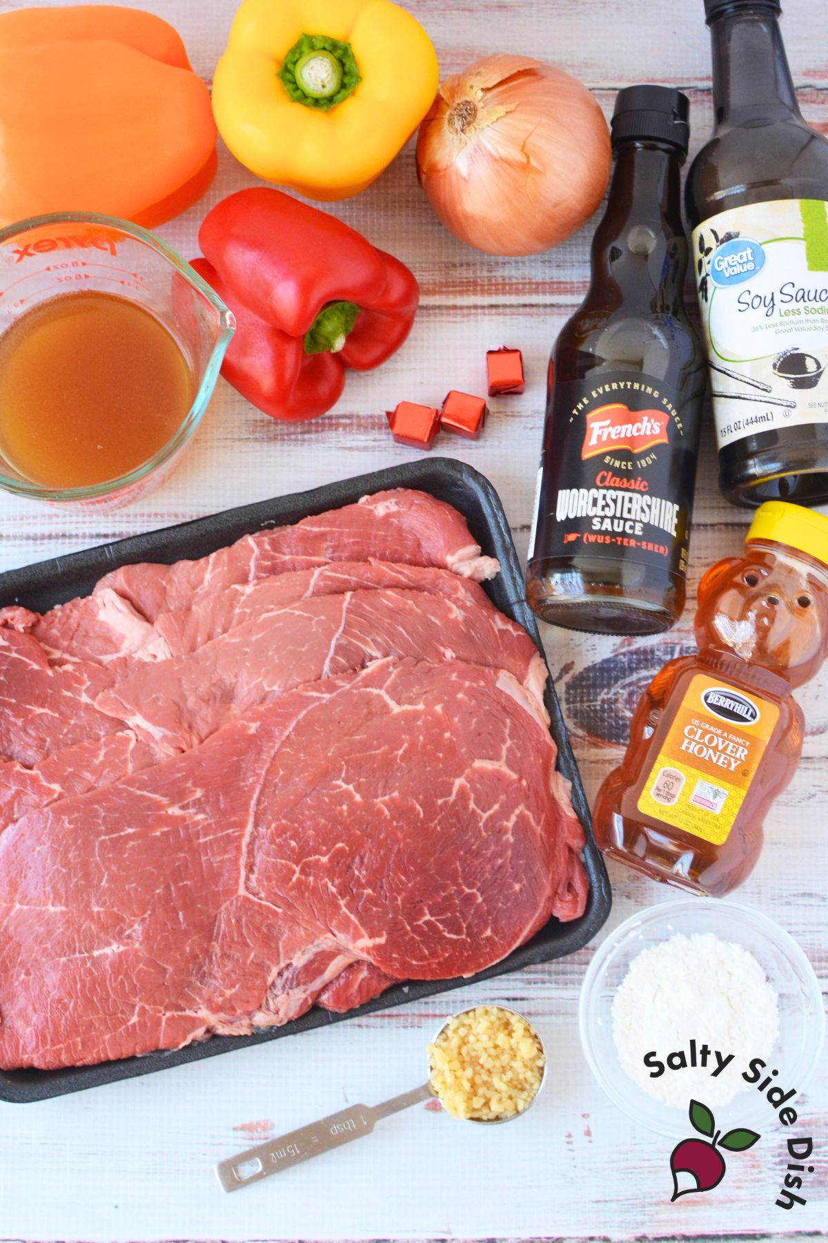 Ingredients for slow cooker steak and peppers including sirloin steak, bell peppers, onion, soy sauce, honey, and beef broth