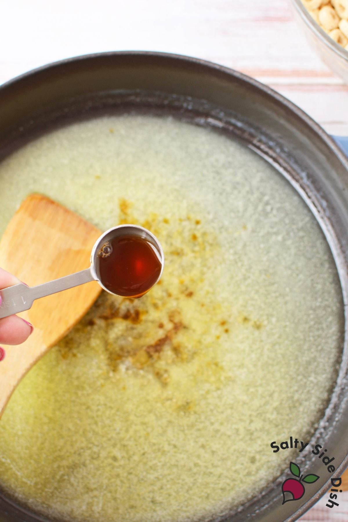 vanilla extract being added to melted butter in skillet for stovetop churro Cheerios recipe