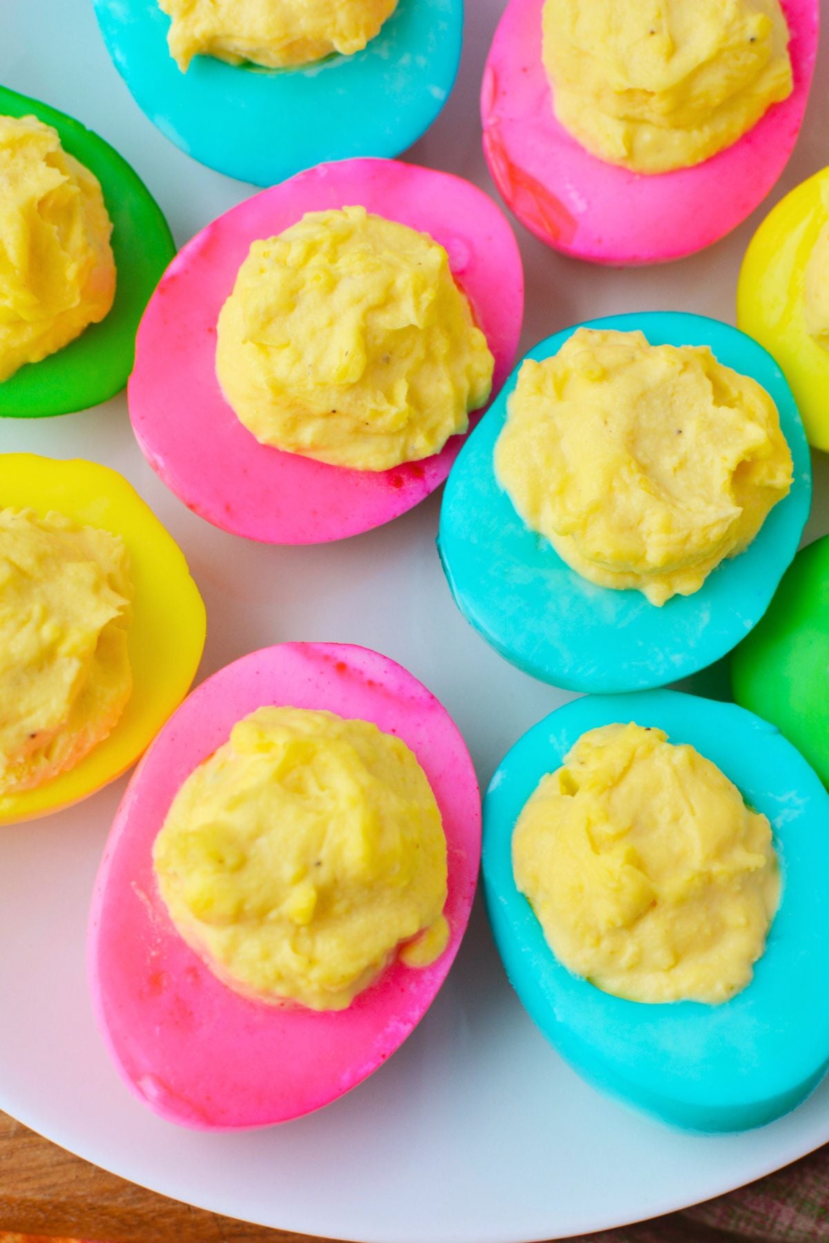 finished colored deviled eggs with bright pink yellow and green egg whites on a serving tray