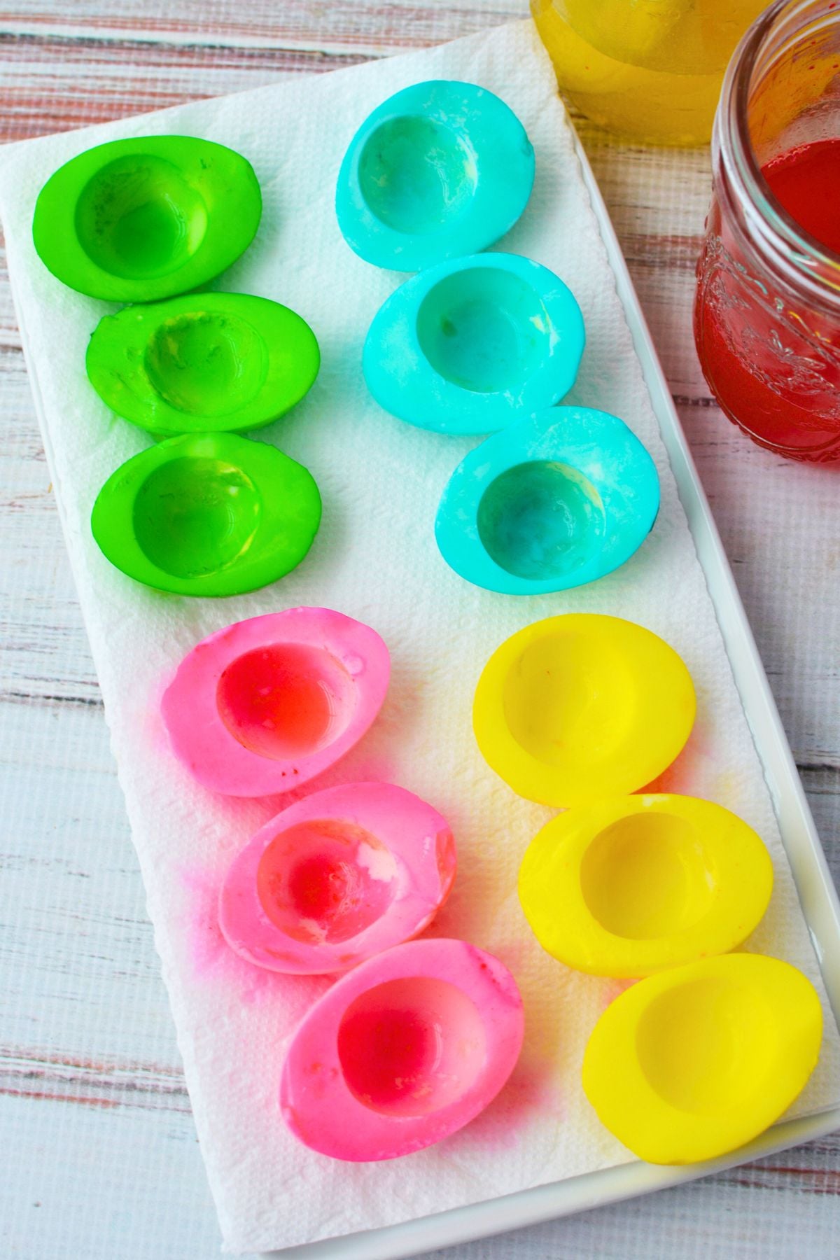 dyed egg white halves in pink yellow blue and green drying on paper towels for colored deviled eggs