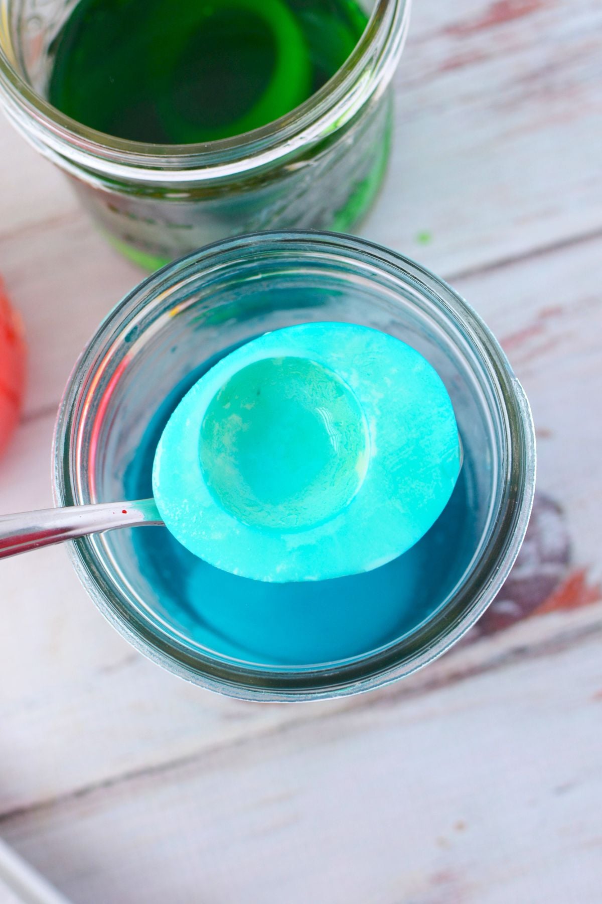 egg white half being dyed blue in food coloring water for colored deviled eggs