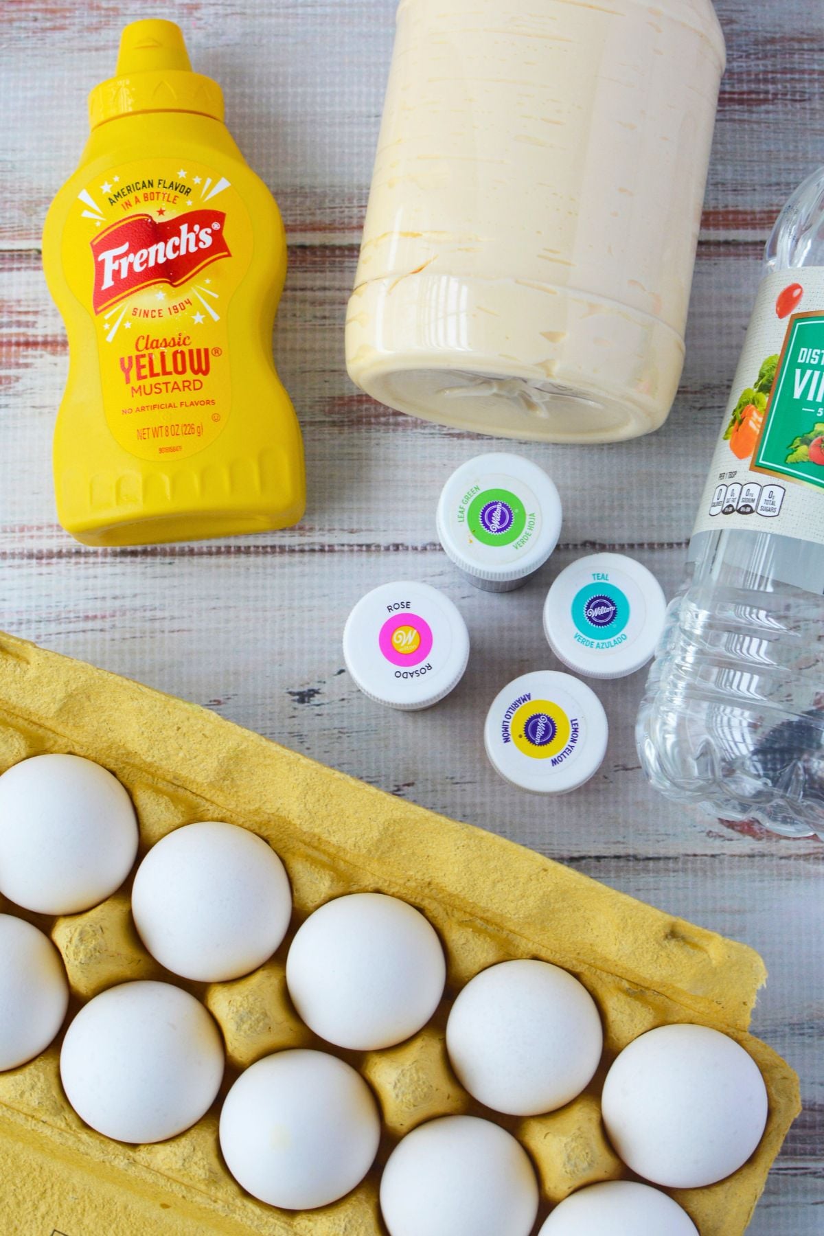ingredients for colored deviled eggs including eggs mayonnaise mustard vinegar and gel food coloring