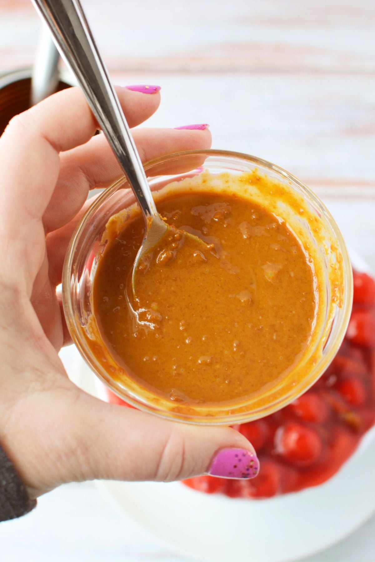 Small bowl of Biscoff cookie butter ready to drizzle over cherry cheesecake