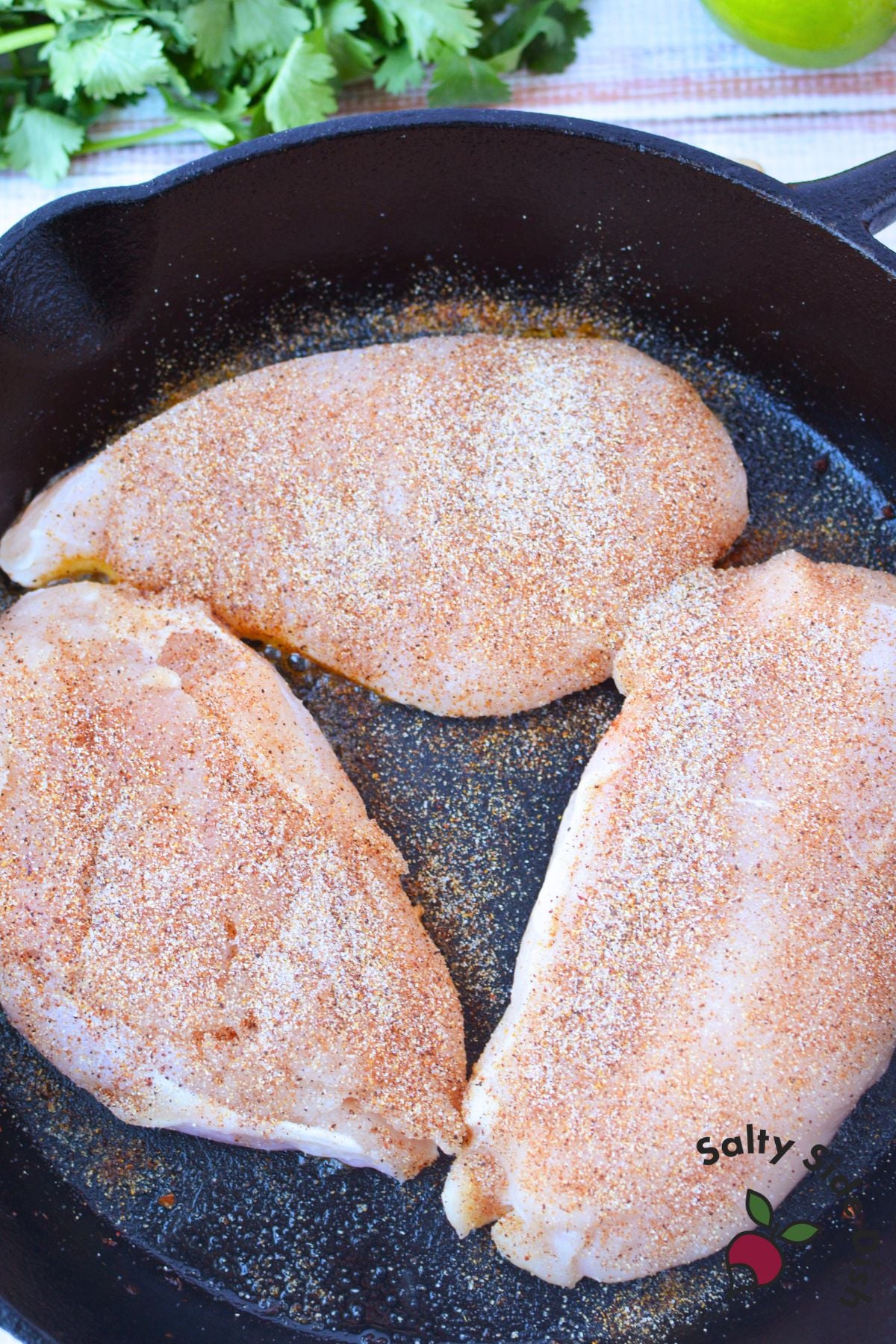 Seasoned chicken breasts with garlic powder, salt, and cayenne in a cast iron skillet for Mexican street corn chicken bake