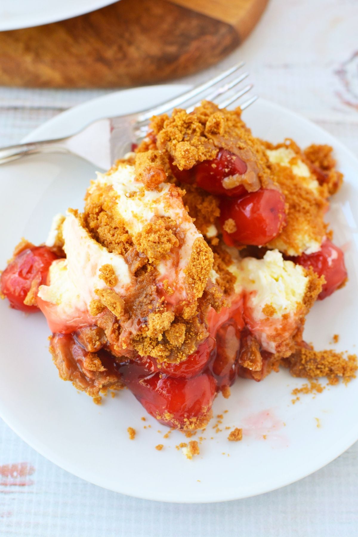 Top view of no bake cheesecake covered in cherry pie filling, cookie butter, and crushed Biscoff cookies