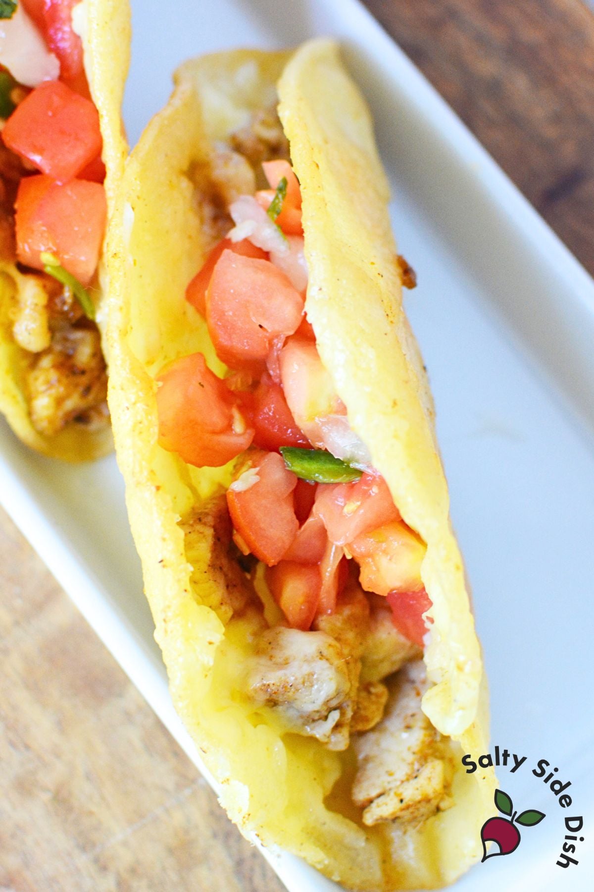 Close-up of finished crispy skillet chicken taco with pico de gallo topping showing crunchy golden shell