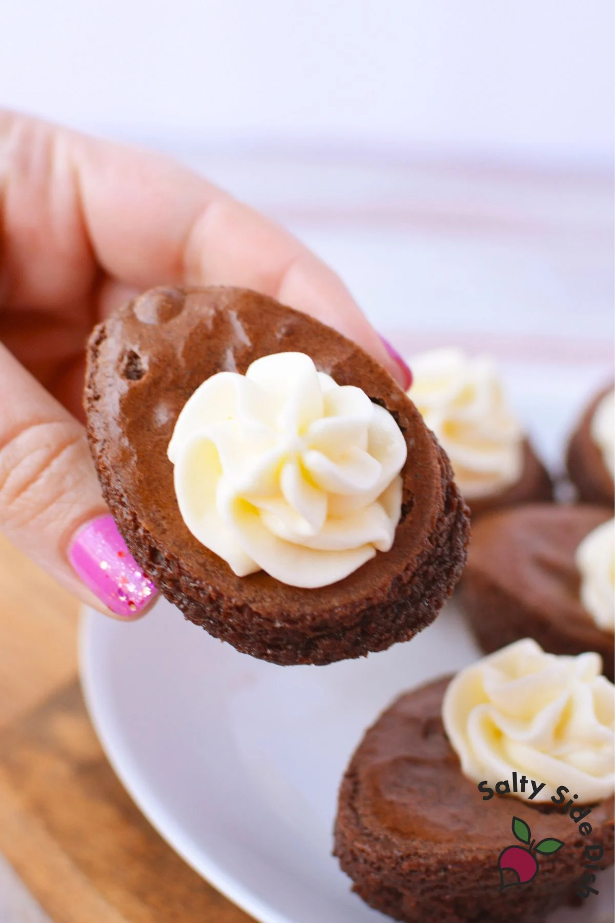 Deviled brownie egg held in hand filled with piped cream cheese frosting