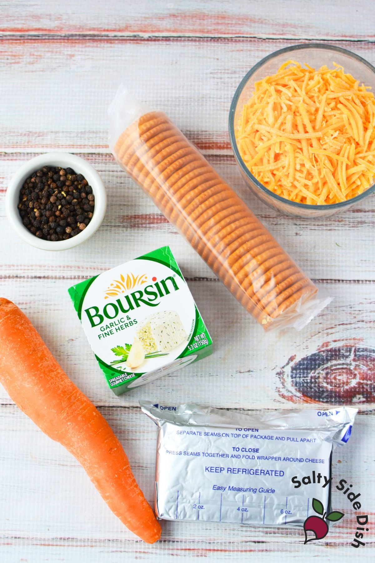 ingredients for mini chick cheeseball bites including Boursin garlic and herb cheese, cream cheese, shredded cheddar, carrot, peppercorns, and round butter crackers