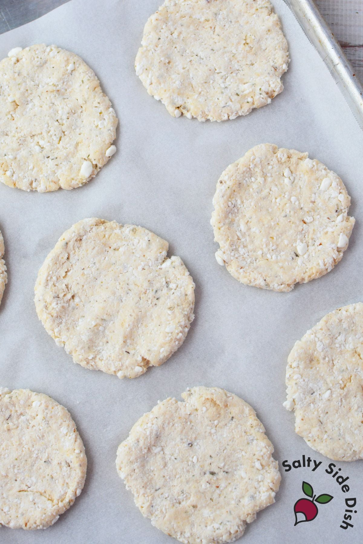 eight unbaked cottage cheese pizza crusts shaped into rounds on a parchment lined baking sheet