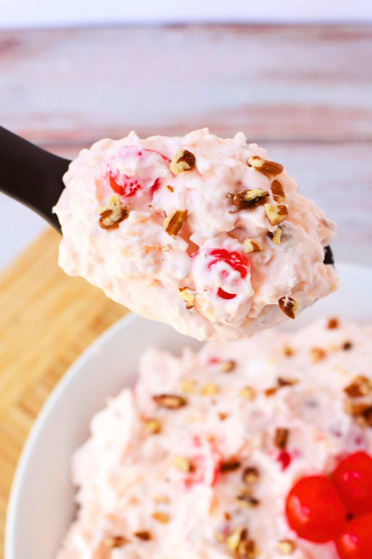 fluff salad recipe with cherries in a spoon.