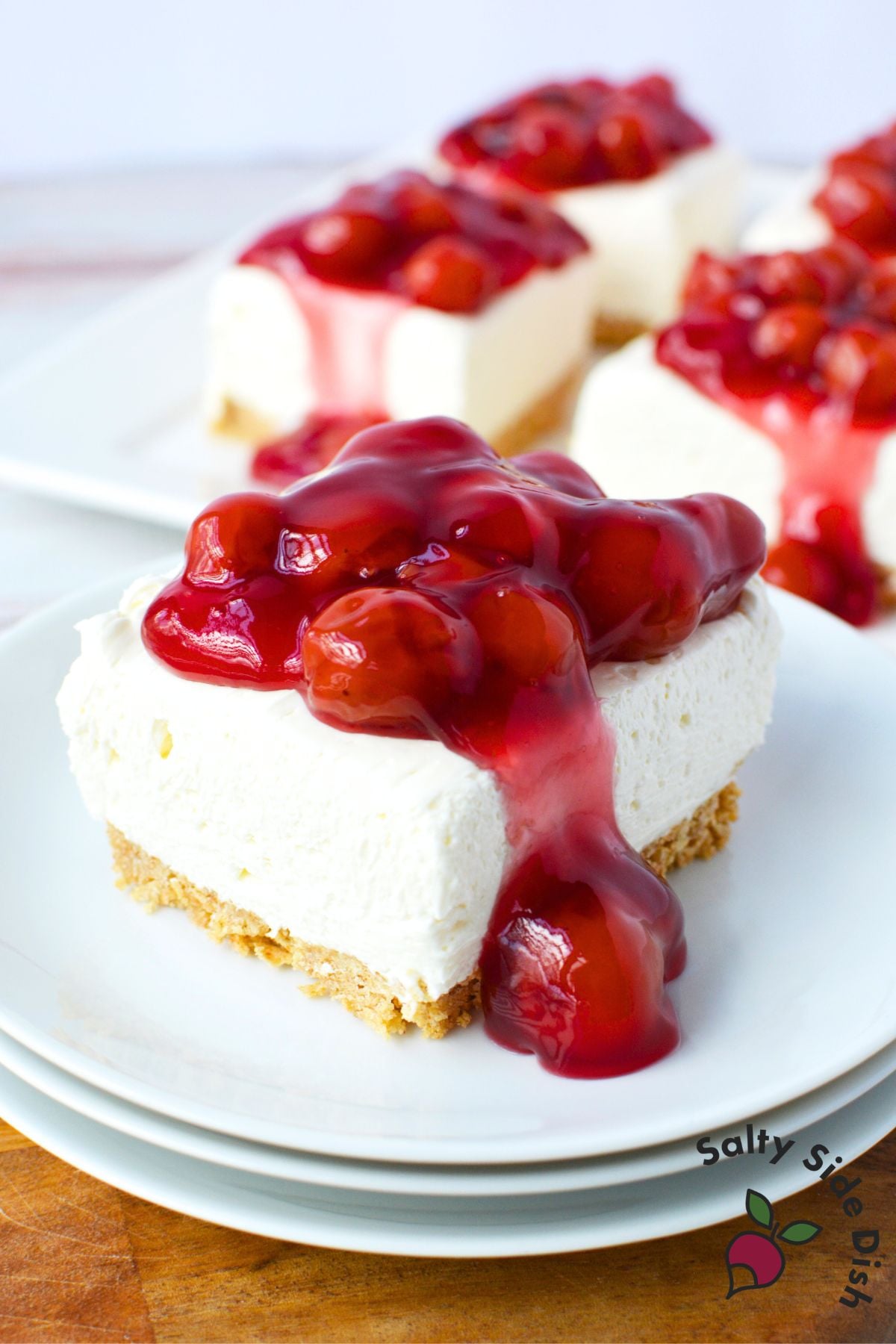 no bake cherry cheesecake bar on white plate topped with glossy cherry pie filling